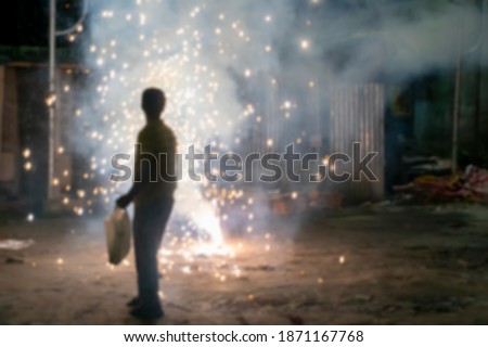 Blurred image of young man lighting up fire crackers at night,event of Kali Puja, a Hindu Indian festival - for spiritual celebration of light over eternal darkness.The fireworks create air pollution. Royalty-Free Stock Photo #1871167768