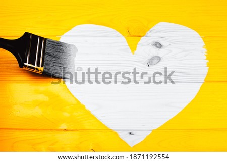 Heart shape of natural wooden background surrounding freshly painted yellow surface. Renovation concept. Demonstrating trendy colors of year 2021 - Gray and Yellow.