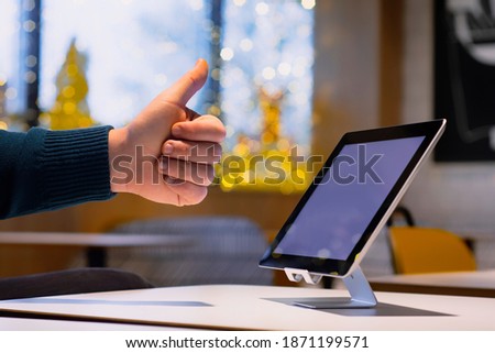 Mock-up Technology. Businessman shows thumbs up on the background of a digital tablet with white screen