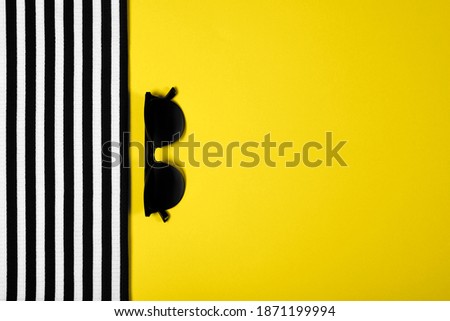 Top view of yellow gray colored striped clothes and sunglasses with copy space. Trendy colors 2021 year.  Summer and vacation concept.