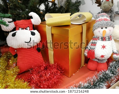 Toy Christmas bull and snowman under the Christmas tree with a gift