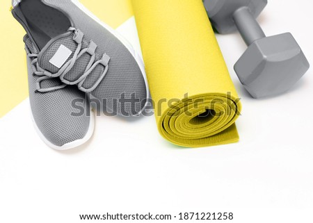 sports on a yellow background, Mat and gray sneakers. . 