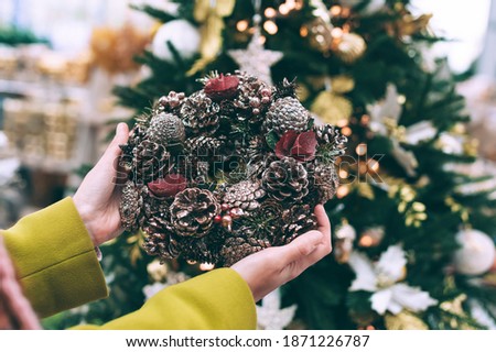 The girl is holding a New Year's wreath in her hands. Against the background of the Christmas tree
