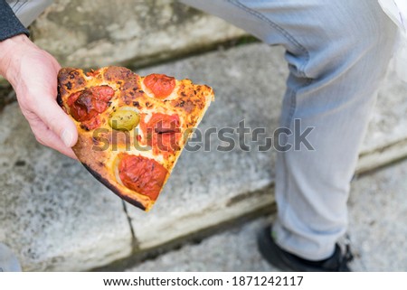 Eating a slice of pizza margherita on the street