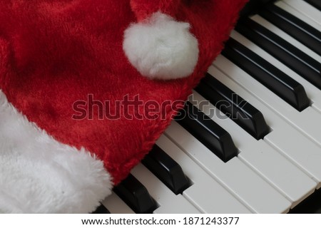 Piano keyboard. Musical background. Piano with red santa hat.