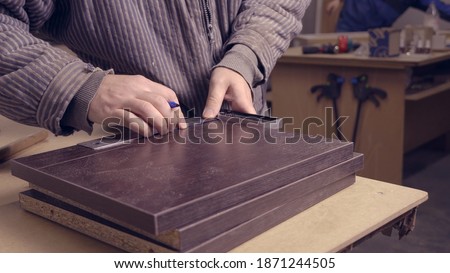 Close-up of master in furniture workshop marking out wooden tiles.