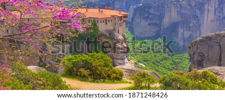 Orthodox Varlaam Monastery in Meteora, Greece on high mountain rock and pink cherry tree flower blossom