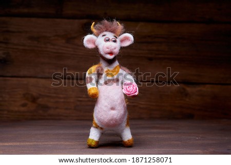 Plush bull toy on a wooden background. A soft toy greets the viewer. Symbol of 2021 New Year.
