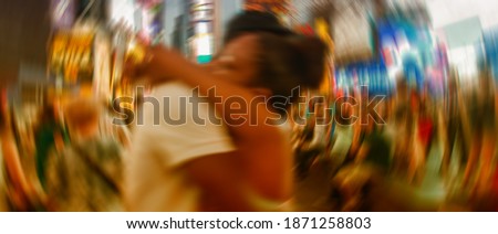 Blurred picture of happy couple embracing among Times Square night lights - New York City.