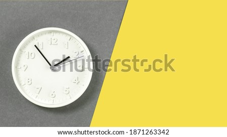Plain wall clock in the center of grey and yellow background. Ten o'clock. Close up banner with copy space, time management or school concept and lunch time. Opening or closing hours. Schedule
