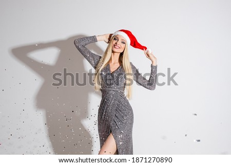 Beautiful young fit girl in Santa hat, sparkling festive dress celebrating 2021 new year, xmas ad photo with copy space
