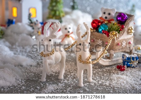 Christmas fabulous composition. Polar bear in a Christmas sleigh with gifts and toys on the background of houses and fir trees in the snow