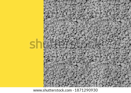 Stripe of illuminating yellow on left of grey stones square,smooth ultimate gray pebbles,pile of rock.Natural texture background,top view,copy space.Design template,mockup,presentation,card,close up