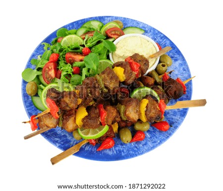 Grilled pork and sweet pepper kebabs on wooden skewers with fresh salad and mayonnaise dip isolated on a white background