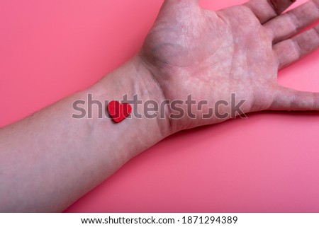 Heart on the wrist of a man's hand on a pink background. The concept of health and happiness.