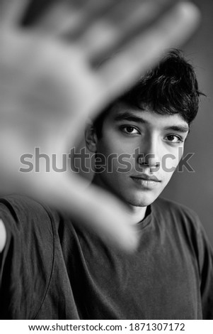 Black and white photo of handsome young man outstretched hand and showing stop hand sign