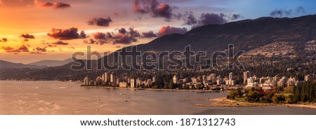 West Vancouver, British Columbia, Canada. Aerial Panoramic View of a modern cityscape on the Pacific Ocean Coast during an Autumn sunny and cloudy sunset. Royalty-Free Stock Photo #1871312743