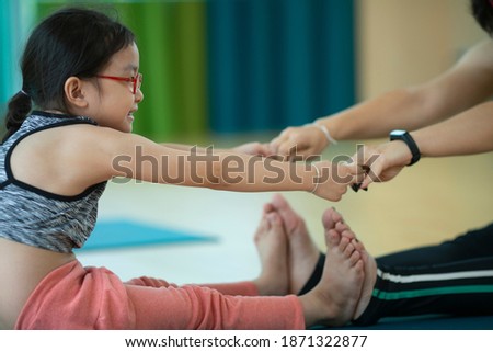 Shot image side view Asian little cute girl with glasses practicing yoga pose on a mat asana indoor, working out wearing sportswear gymnastic exercises. Healthy Sport Activity Meditation Concentrate  