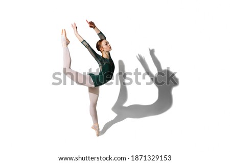Graceful female ballet dancer posing isolated over white background with shadow.