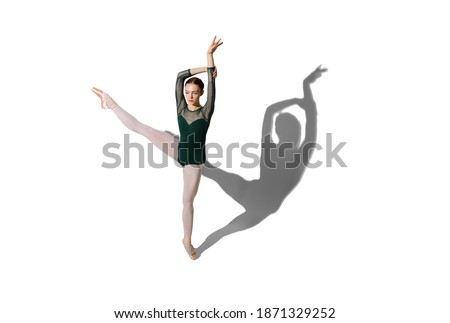 Graceful female ballet dancer posing isolated over white background with shadow.