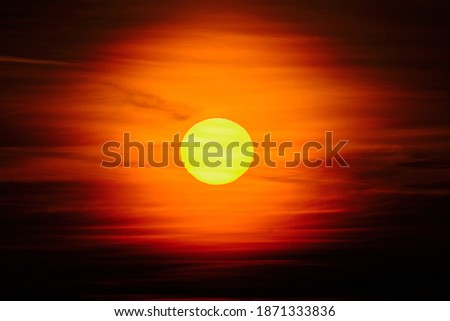 Close-up sunset through the clouds. Big orange sun.