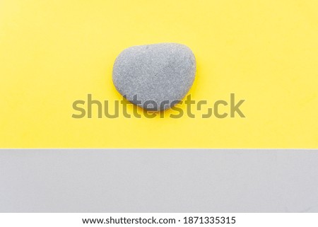 abstract modern handmade paper background with a stone in ultimate gray and illuminating yellow colors