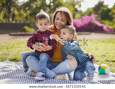Beautiful latin mother enjoy playful time with twin sons in nature park - Children and soap bubbles - Family love