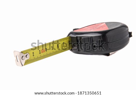 Construction tape measure in black, lying on its side with an open tape. Isolated on a white background. Close up