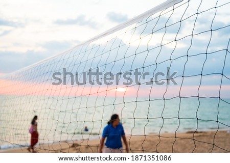 Selective focus volleyball net and out of focus tourist playing volleyball sand beach on blue sky background.Outdoor sport concept.
