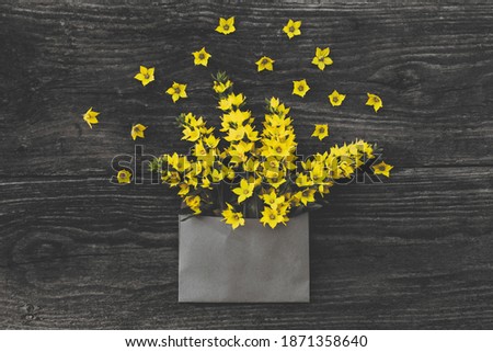 Blank craft envelope with yellow flowers on vintage gray wooden table. Gift, summer mood. Flat lay, copy space. Trendy color of 2021 year.