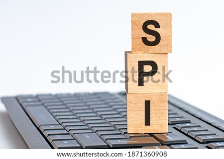 SPI word on wooden block sign on a keyboard, white background. SPI - short for Serial Peripheral Interface