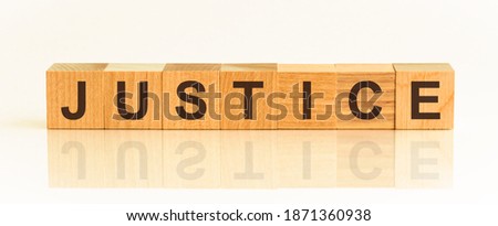 Wooden blocks with the text: justice. The text is written in black letters and is reflected in the mirror surface of the table