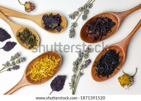 Creative layout made of wooden spoons, green tea, black tea, fruit and herbal tea on white background. Flat lay, copy space. Food concept.
