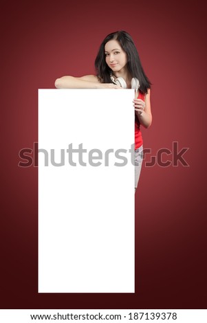 Teenage girl with headphones, holding blank sign. Isolated on red background