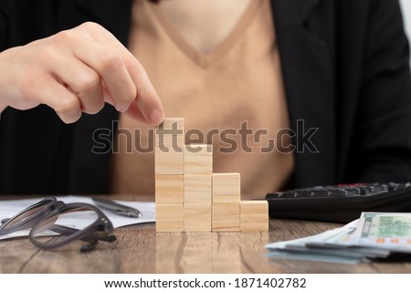 Business woman accounting and banker doing calculations. Concept of success rising with wooden cube.