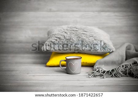 Pillows and cup of beverage against blurred wooden wall as symbol of warmth and comfort at home