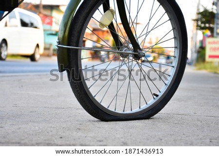Bicycle rear wheel which is flat and parked on pavement to fix and change the new one and inflate, bokeh sunlight background. 