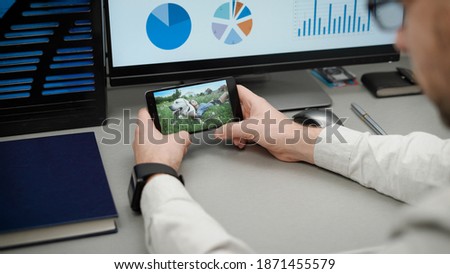 Manager at work, browsing video on the smartphone. Sitting in the office, you can distract yourself and watch the video over the Internet. Royalty-Free Stock Photo #1871455579