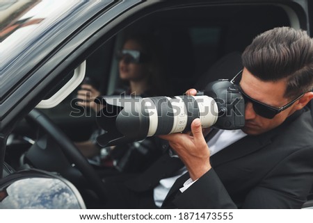 Private detectives with modern camera spying from car