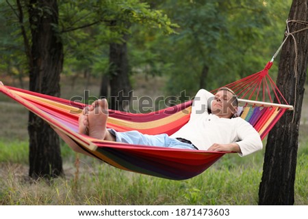 Man resting in comfortable hammock at green garden