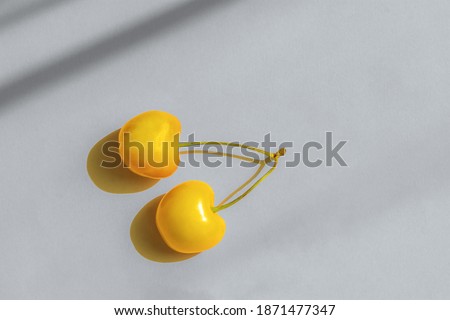 Yellow cherry on a gray background. Representation of the color of the year 2021 ultimate gray and illuminating color. A top view of a flat layout. The concept of sunny mood, summer. Fruit minimalism.