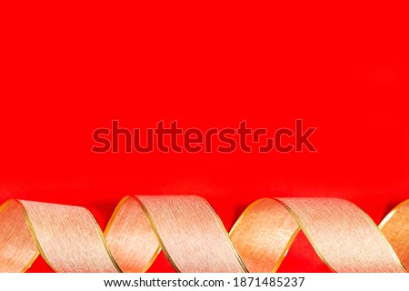 Golden ribbon against red background. gold packaging ribbon curls on red background, new year background, copy space, place for text, banner, holiday concept, Christmas, new year, Valentine's day