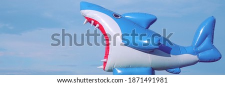 Inflatable Shark On Blue Background. Toy Shark With Open Jaw, Closeup View. Rubber Inflatable Shark And Sky Background. Sea Beach Or Pool Kids Toy.