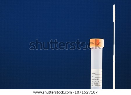   Analysis test to detect SARS-CoV-2 RNA by PCR, swab, transparent vial with data sticker and orange closure.Blue background. Royalty-Free Stock Photo #1871529187