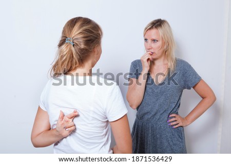 Mother asking her teenage daughter. Girl wants to lie to her parent and crossed her fingers. Royalty-Free Stock Photo #1871536429