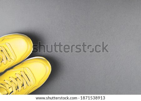 Yellow sneakers on grey background. Concept of sport and healthy lifestyle. Colors of year 2021. Place for text, flat lay, top view.