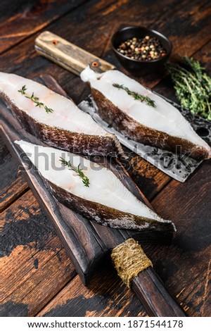 Raw halibut fish steak. Dark wooden background. Top view