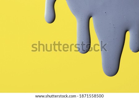 Smears of Ultimate Gray paint on a yellow background Illuminating trending colors of 2021