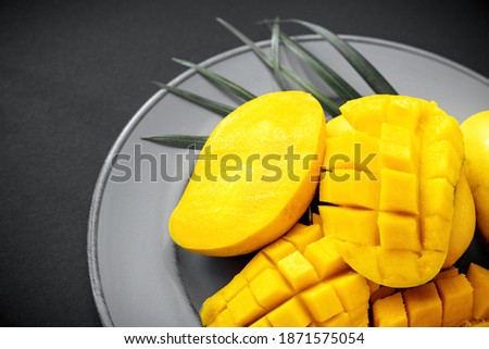 Pantone colors of 2021. Yellow ripe mango half cut slice diced on gray plate. Summer tropical food in trendy color.