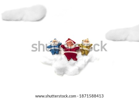 A collage of colorful glittery Santas laying in the clouds, top view of plain white background